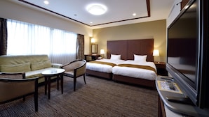 A hotel room with a sofa, two single beds, a TV, a desk with a lamp, and a chair. - HOTEL GRANDSPA AVENUE (Asakura)