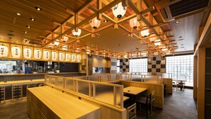 A restaurant interior with wooden paneling, booths, and a bar area. - HOTEL GRANDSPA AVENUE (Asakura)