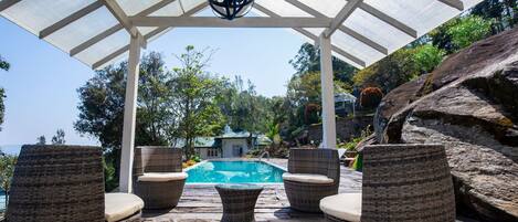 Una piscina al aire libre, sillones reclinables de piscina