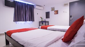 Een hotelkamer met twee bedden, een aan de muur bevestigde televisie, een airconditioning en een deur met een hendel.
