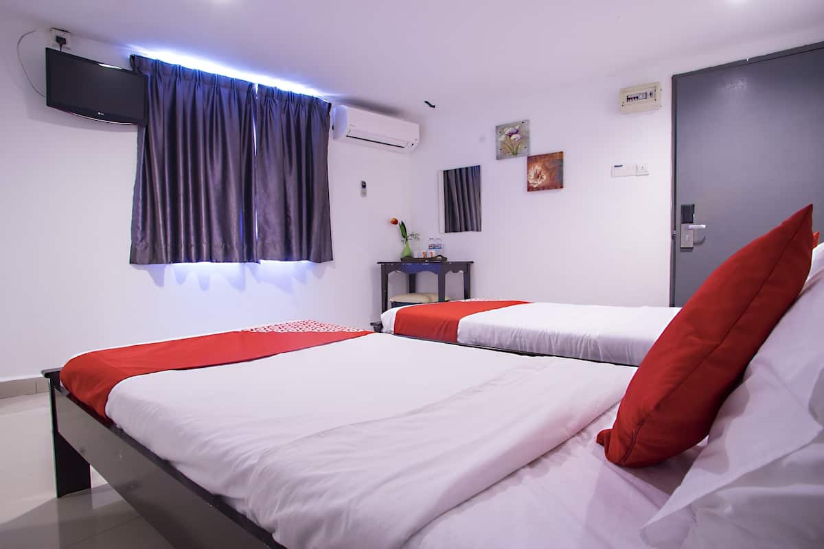Habitación de hotel con dos camas, un televisor montado en la pared, un equipo de aire acondicionado y una puerta con manija.
