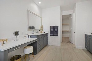 Une salle de bain moderne avec un grand miroir, un meuble-lavabo et un dressing.