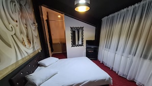 Une chambre d’hôtel avec un grand lit, une télévision, un miroir et une moquette rouge.