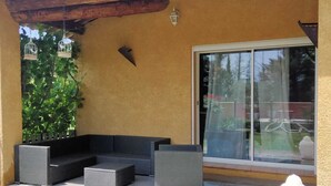 Katettu terassialue, jossa on sisäänrakennettu istuinalue, liukuovi ja pieni Buddha-patsas.