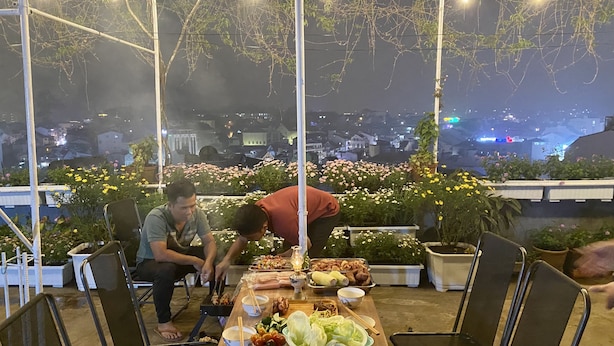 Un espace extérieur aménagé pour les repas, avec une table dressée, entouré de plantes et de fleurs en pot.