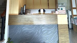 A modern kitchen with wooden cabinets, a central island, and a unique ceiling design. - Happiness Inn (Hengchun)