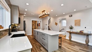 A modern kitchen with white countertops, wooden flooring, and a central island. - Powder Pointe by AvantStay | Minutes From Base Village (Park City)