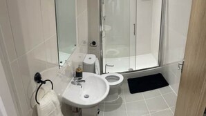 A modern bathroom with a toilet, sink, and shower. - A newly built 2023 apartment (Oxford)