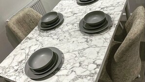 Une table à manger avec un plateau en marbre et quatre assiettes noires empilées dessus.