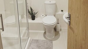 Une salle de bain moderne avec une douche à parois de verre, des toilettes, un lavabo et une petite plante en pot.