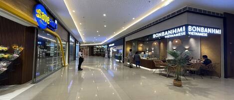 A modern shopping mall interior with a 'Save More' store and a 'Bonanham Vietnamese' restaurant.