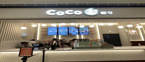 A Coco store with a modern design, featuring a counter, digital menu displays, and a clean, well-lit interior.