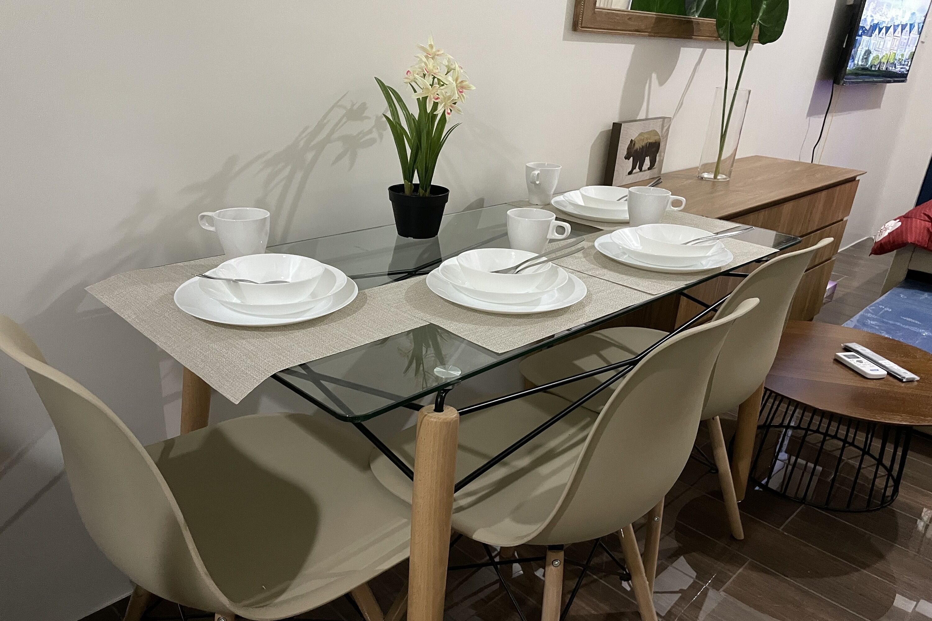 Een eettafel met witte borden, bekers en een potplant.