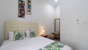 A hotel room with a large bed, a bedside table with a lamp, a mirror, and two paintings on the wall.