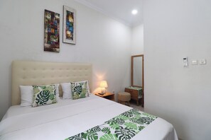 Une chambre d’hôtel avec un grand lit, une table de chevet avec une lampe, un miroir et deux tableaux accrochés au mur.