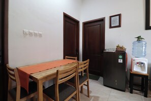 A small dining area with a wooden table and chairs, a water dispenser, and a refrigerator. - Bisma Balcony Homestay (Pogung Lor)