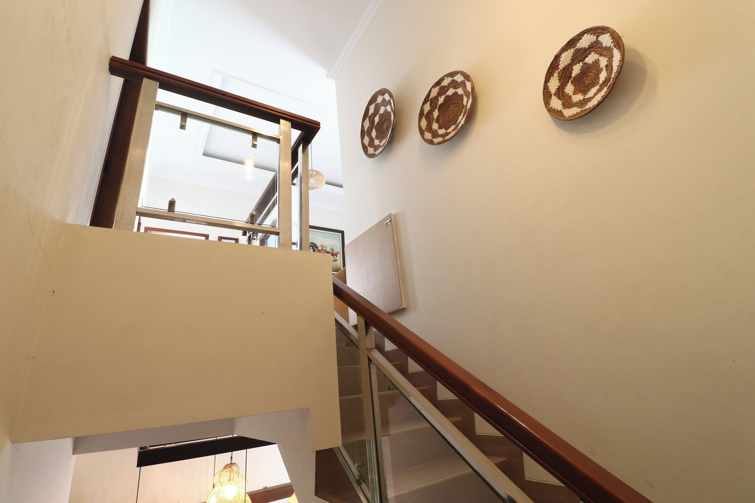 A staircase with glass railings and a wooden handrail, leading to an upper floor.