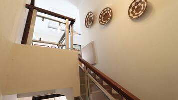 A staircase with glass railings and a wooden handrail, leading to an upper floor.