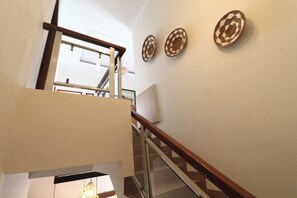 Un escalier avec des rampes en verre et une main courante en bois, menant à l’étage supérieur.