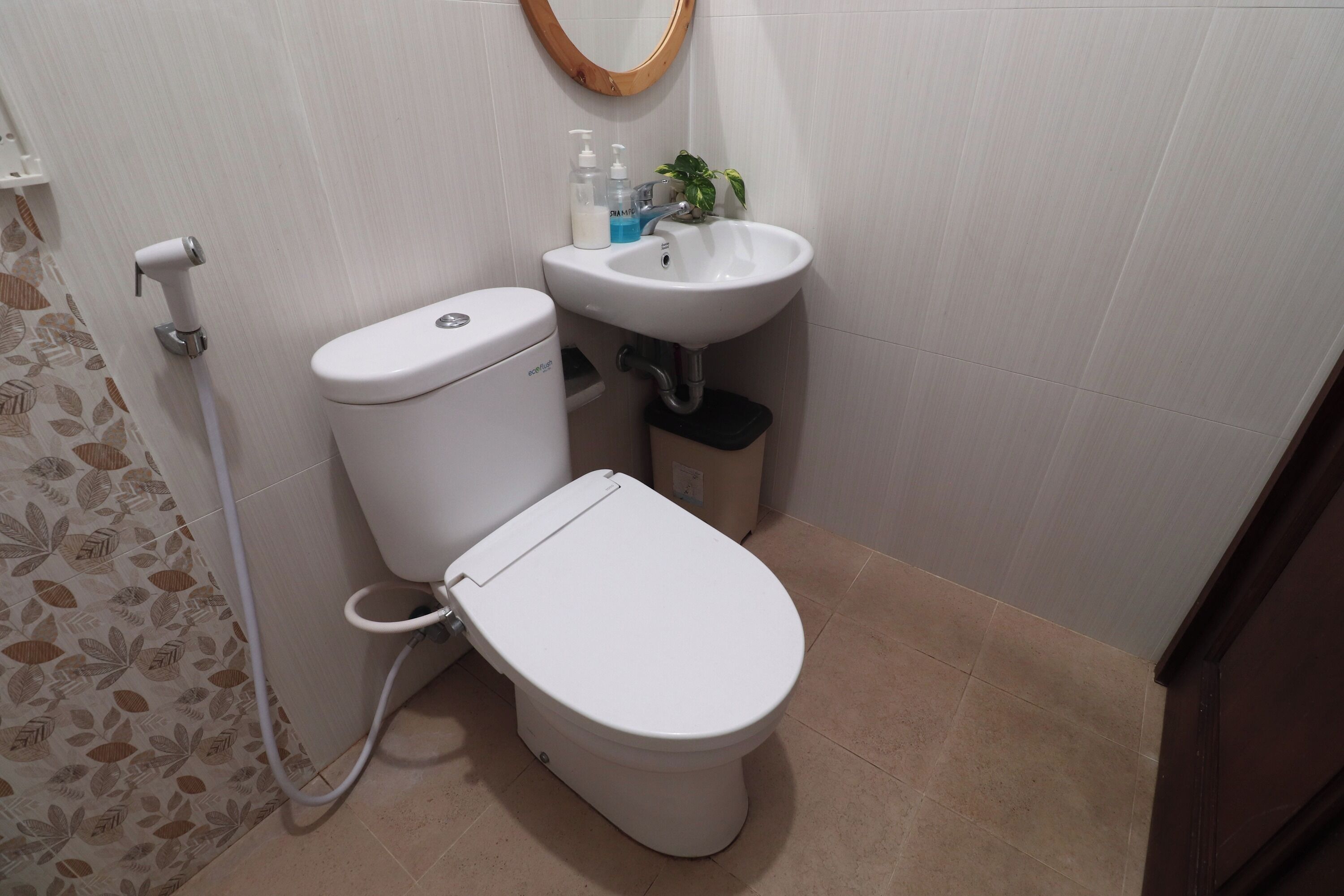 A bathroom with a toilet, sink, and a handheld showerhead.