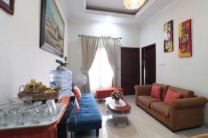 A living room with a sofa, a table with glasses, a water dispenser, and a painting on the wall.