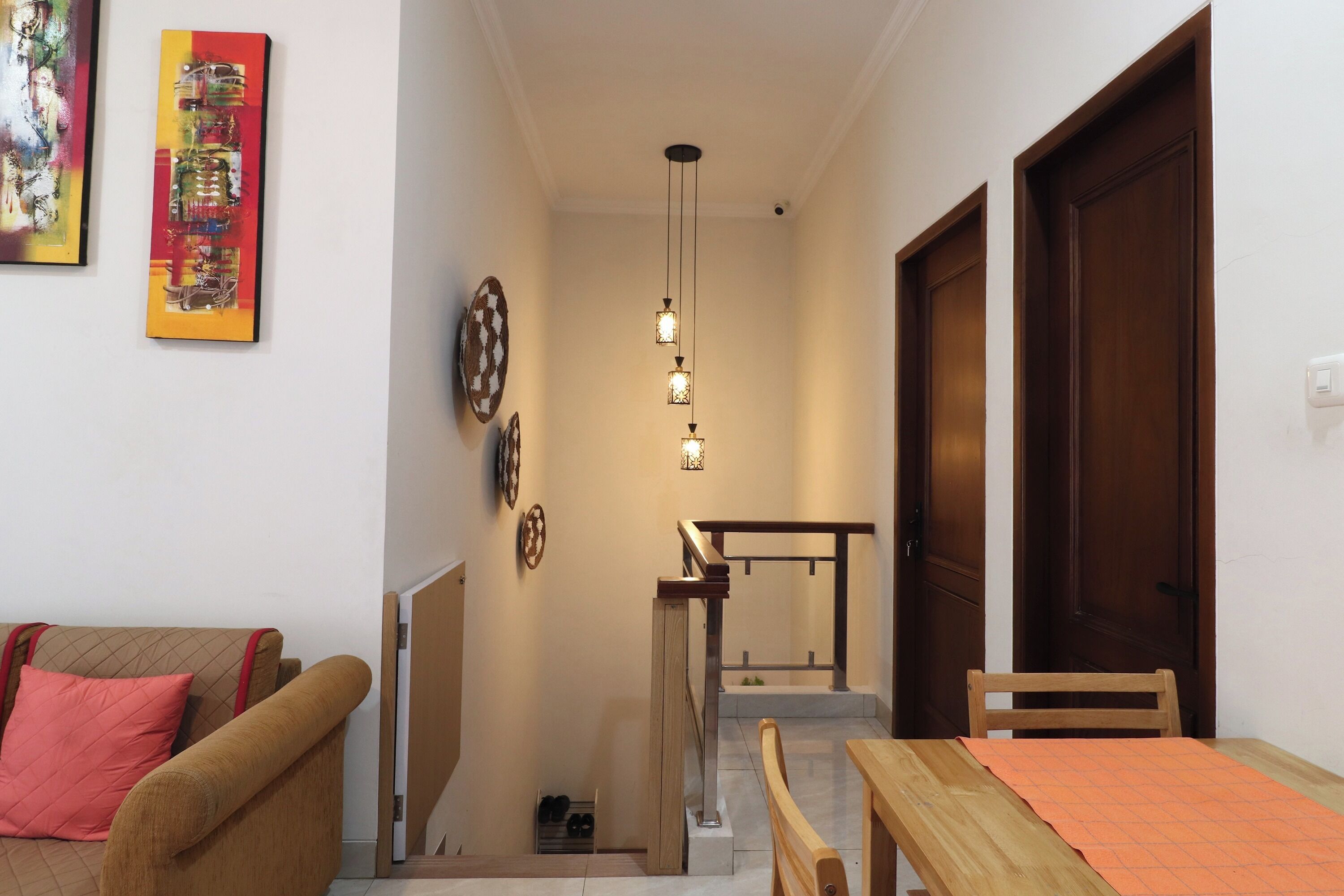 A hallway with a staircase, a wooden door, and a dining area with a table and chairs.