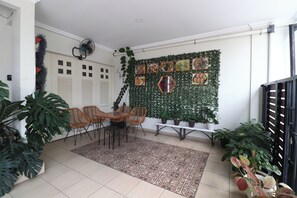A room with a dining area, a wall decorated with food pictures, and potted plants. - Bisma Balcony Homestay (Pogung Lor)
