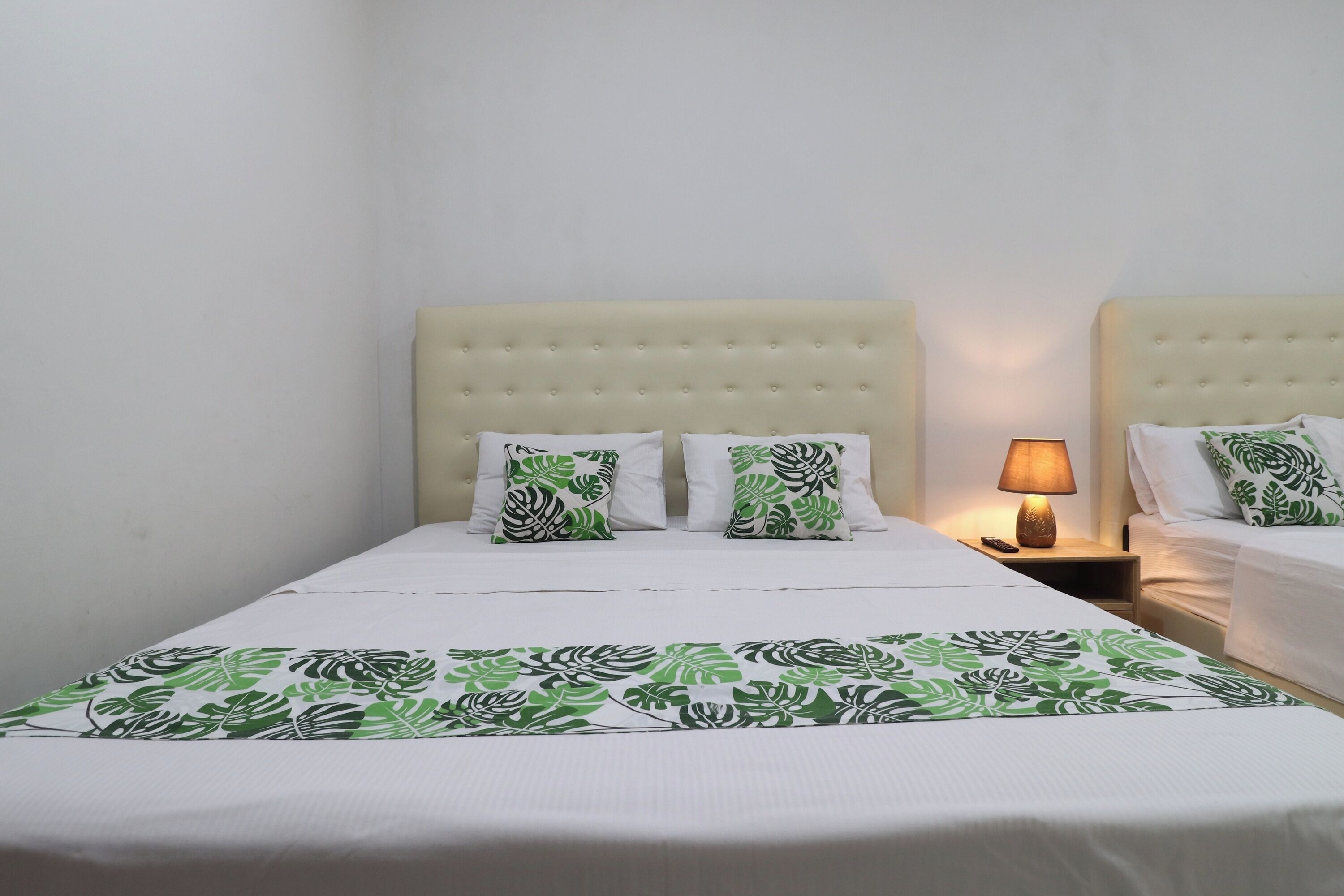 A hotel room with a bed, two nightstands, a lamp, and a patterned bedspread.