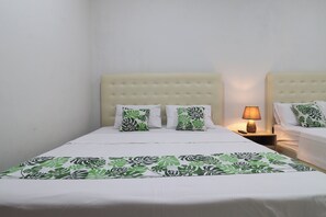 A hotel room with a bed, two nightstands, a lamp, and a patterned bedspread. - Bisma Balcony Homestay (Pogung Lor)