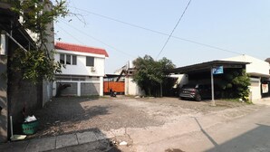 A residential area with a white building, a red-tiled roof, and a parked car. - Bisma Balcony Homestay (Pogung Lor)