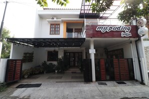 A two-story building with a covered entrance, a sign for 'my.puding joga', and a gated driveway. - Bisma Balcony Homestay (Pogung Lor)