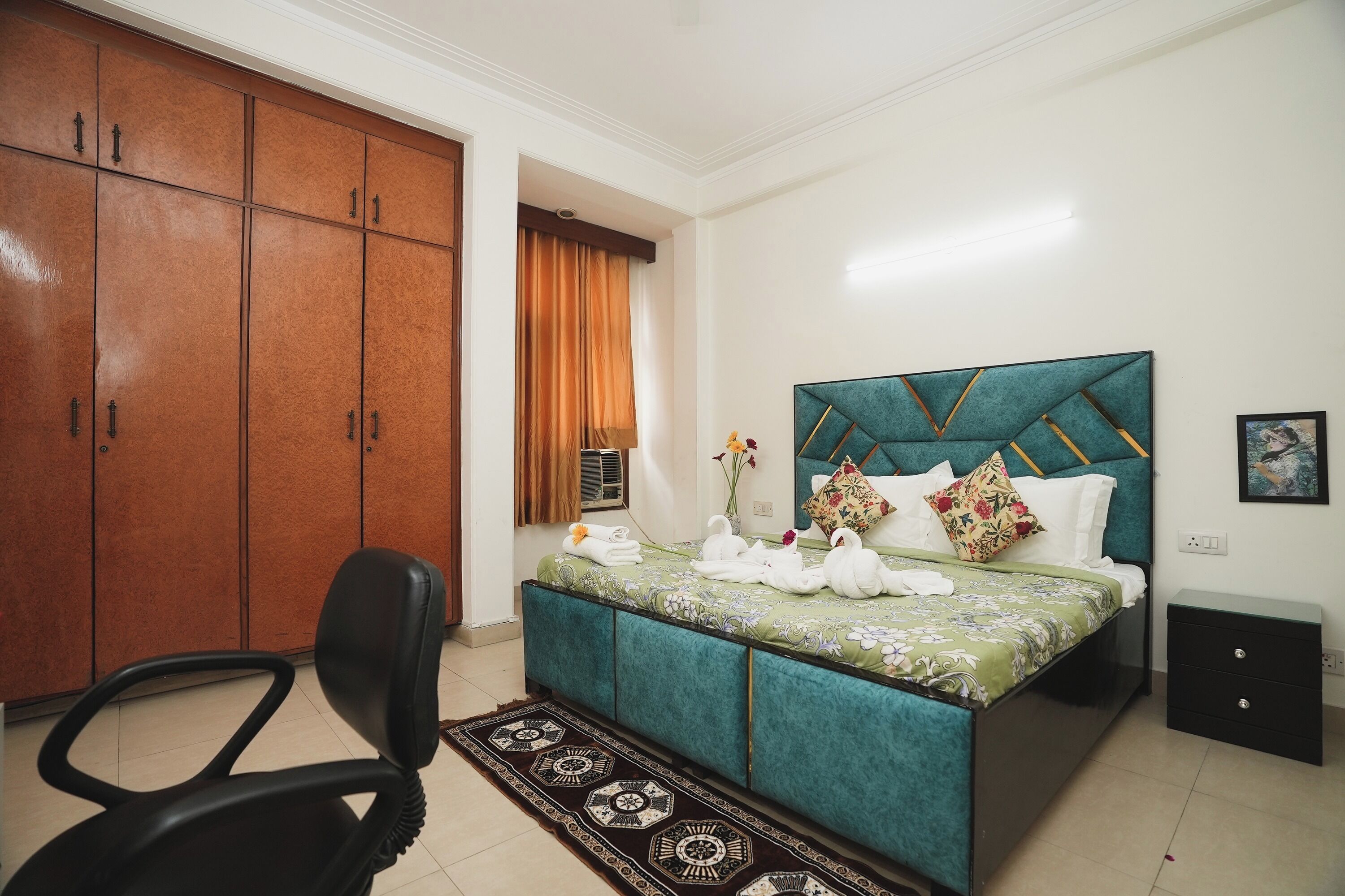 A bedroom with a bed, a chair, a wardrobe, and a nightstand.