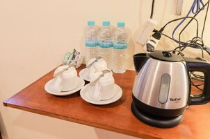 Una mesa con tres botellas de agua, una tetera y dos tazas con cucharas.