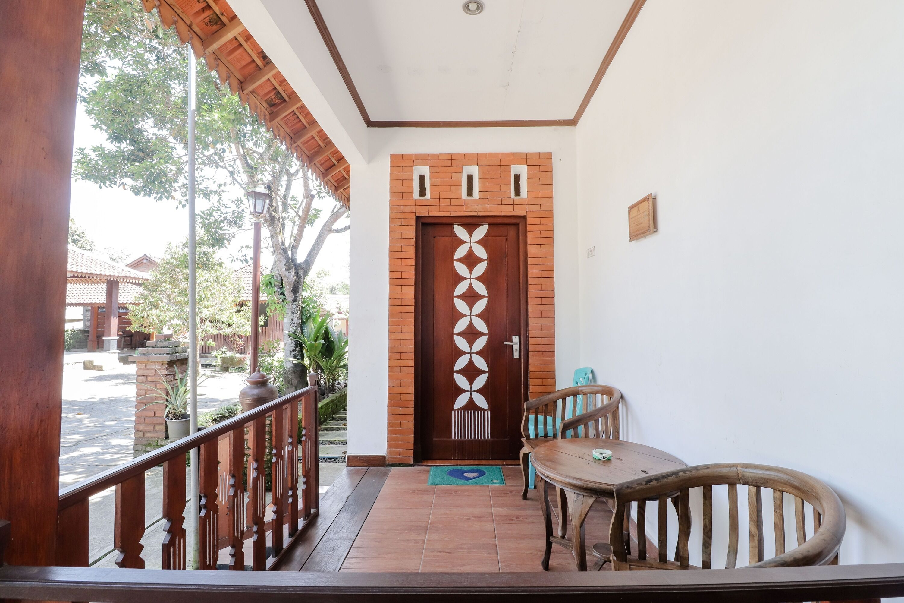 A wooden door with a geometric design, a small table with chairs, and a balcony with a wooden railing.