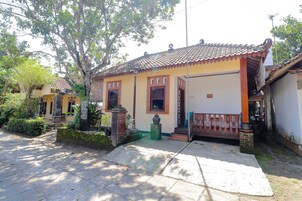 Una casa tradicional con techo de tejas, un porche y un pequeño jardín.