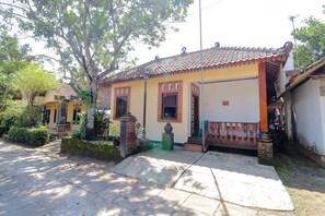 Una casa tradicional con techo de tejas, un porche y un pequeño jardín.