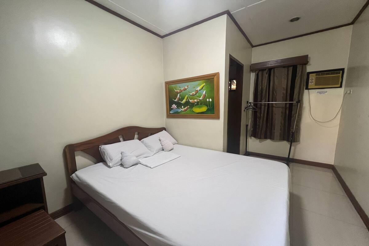 Una cama bien tendida con sábanas blancas en una habitación de hotel.