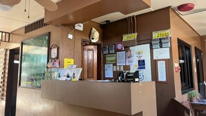 A reception desk with various notices and a business license plate. - Tenzai Homestay (Puerto Princesa)