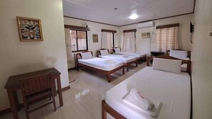 A hotel room with three single beds, a wooden desk, and a small table. - Tenzai Homestay (Puerto Princesa)