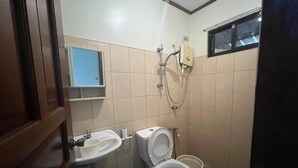A small bathroom with a toilet, sink, and shower. - Tenzai Homestay (Puerto Princesa)