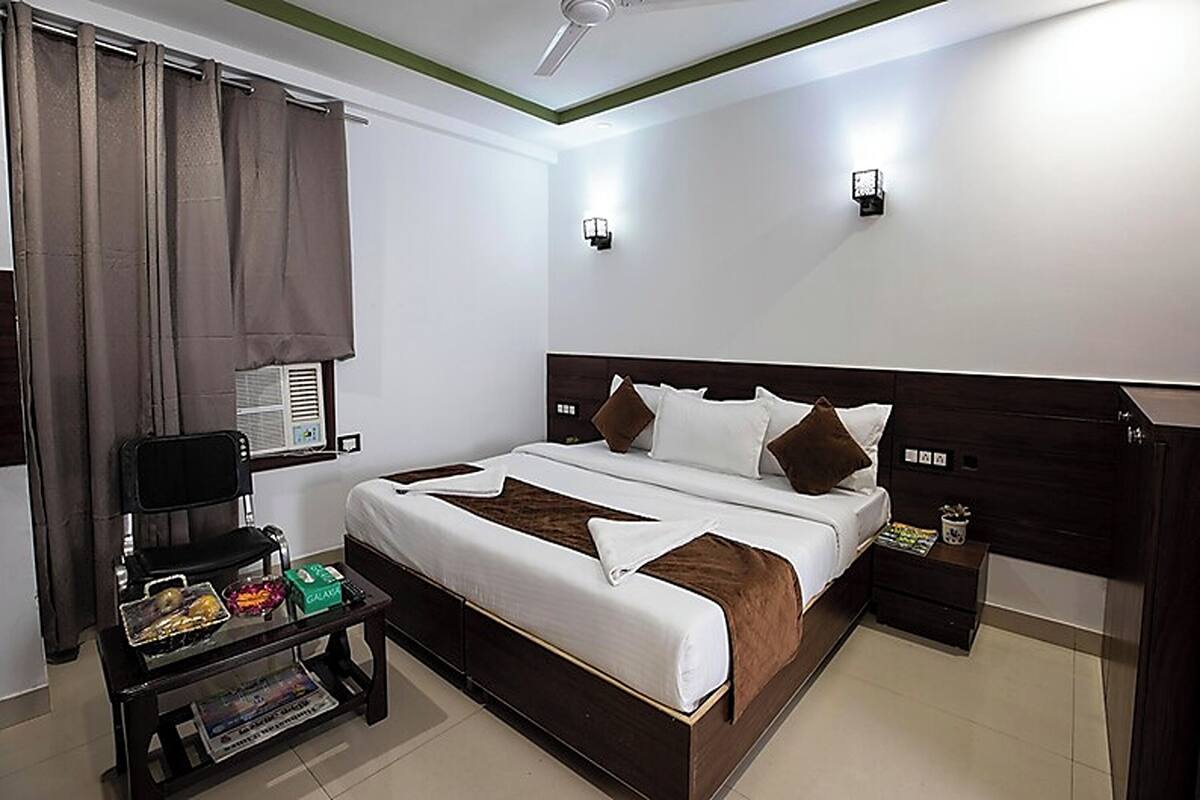 A neatly arranged bedroom with a bed, bedside tables, a chair, and a small table with items on it.