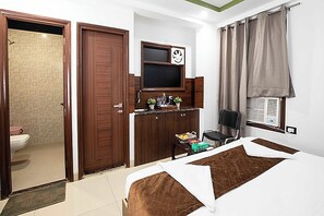 A hotel room with a bed, a television, a desk, and a window with curtains. - HR Grand Hotel (New Delhi)