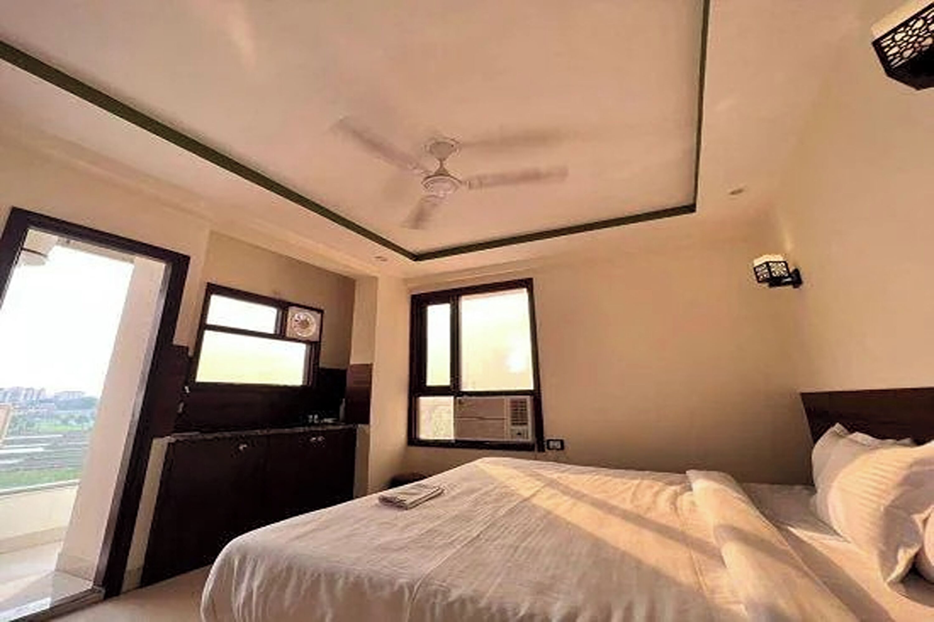 A hotel room with a bed, a ceiling fan, a window, and a desk with a chair.
