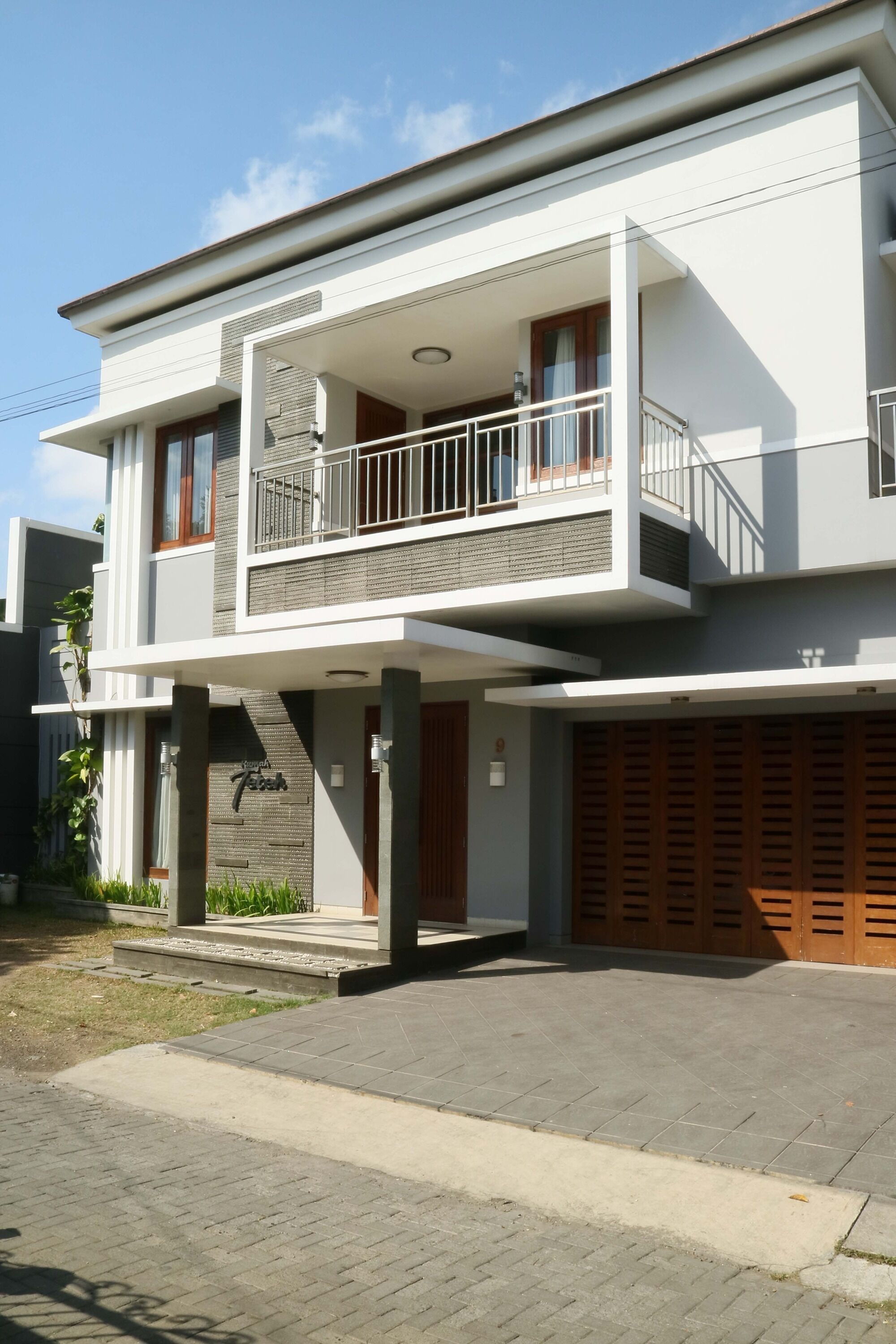 Uma casa moderna de dois andares com varanda, garagem e um jardim bem cuidado.
