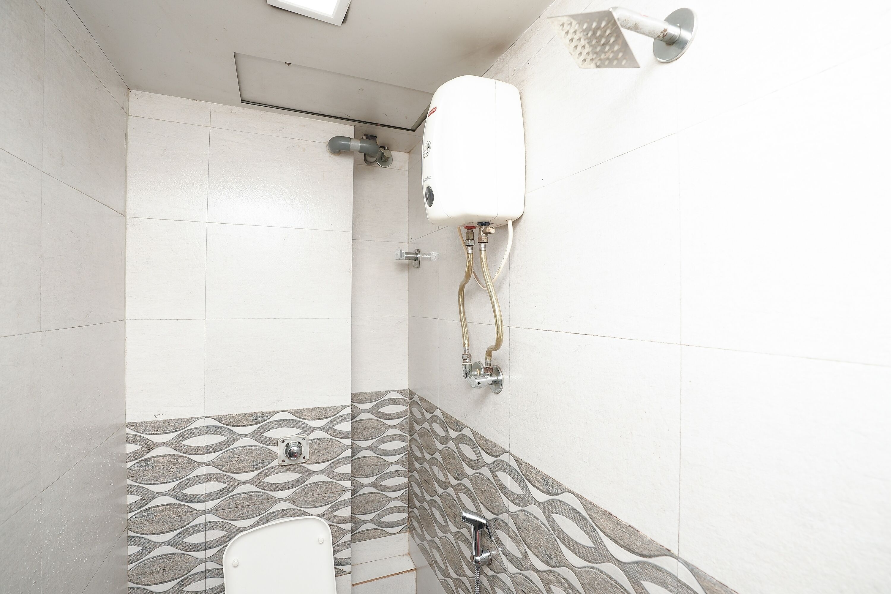 A bathroom with a shower, toilet, and a water heater mounted on the wall.