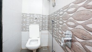 Un baño pequeño con azulejos, un inodoro, ducha y un revestimiento de pared estampado.