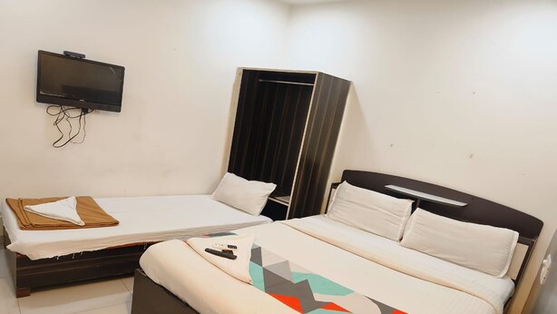 Habitación de hotel con dos camas, un televisor montado en la pared y un armario.
