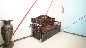 A corner room with a sofa, a large vase, and a clock on the wall. - Hotel Havana (Mumbai)