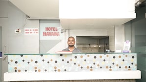 A hotel reception desk with a check-in/out sign, a QR code for room access, and a modern design with a patterned countertop. - Hotel Havana (Mumbai)