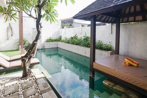 A swimming pool with a wooden deck and a covered seating area. - Queen Rose Villa & Spa (Jimbaran)